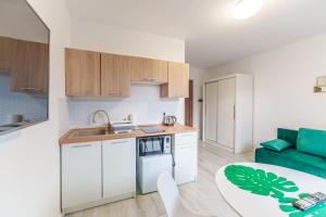 a kitchen with white cabinets and a green couch at Apartament Tropikalny by Holiday&Sun in Grzybowo