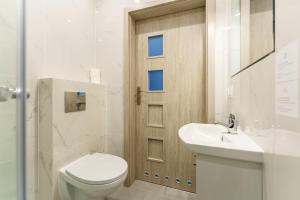 a bathroom with a toilet and a sink and a door at Apartament Tropikalny by Holiday&Sun in Grzybowo