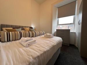 a bedroom with a large bed with towels on it at Partick Apartment in Glasgow