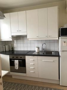 a kitchen with white cabinets and a sink and a stove at Kemi city center 2 room and kitchen Free private parking in Kemi