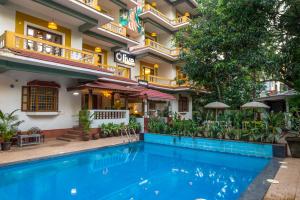 a hotel with a swimming pool in front of a building at Olive Calangute Niwasa - by Embassy Group in Calangute