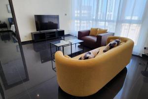 a living room with a yellow couch and a television at Smart Stay Salmiya apartment in Kuwait