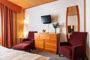 Hotel Schwarz في Nové Hamry: غرفة فندقية فيها كرسيين وتلفزيون