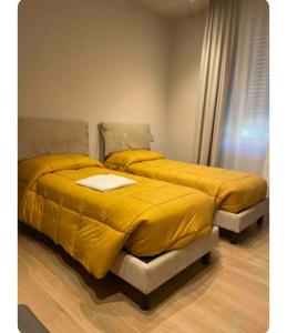 two beds with yellow covers in a room at Théa apartment in San Benedetto del Tronto