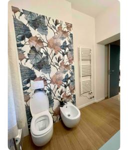 a bathroom with a toilet and a flowery wall at Théa apartment in San Benedetto del Tronto