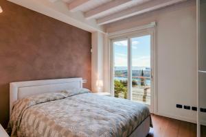 sypialnia z łóżkiem i dużym oknem w obiekcie WOW - amazing lake view! w mieście Salò +16 zdjęć