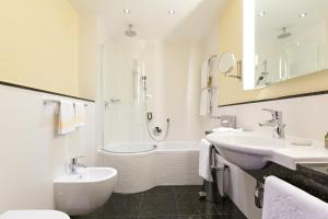 a bathroom with a tub and a sink and a shower at Hotel Kaiserhof Wien in Vienna