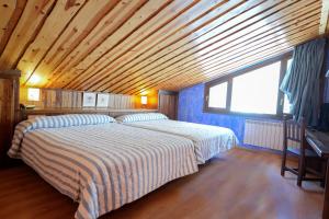 a bedroom with two beds and a wooden ceiling at HOTEL TURPÍ in Benasque
