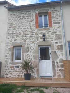 een stenen huis met een witte deur en een potplant bij Maison de charme L'hirondelle en Auvergne in Champs