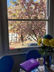 een tafel met een vaas met bloemen en een raam bij Coastal Apartment in Southend-on-Sea