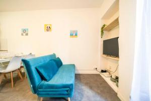 sala de estar con sofá azul y mesa en Studio - centre historique, en Agde