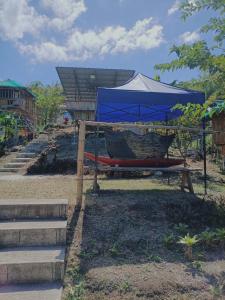 a hammock with a blue umbrella and stairs at Bon Joy's Transient House in Mabini