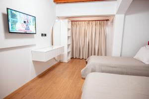a hotel room with two beds and a flat screen tv at Fabio Guest House in Gjirokastër