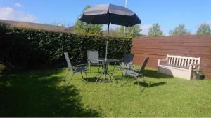 a table and chairs with an umbrella and a bench at The Cozy Stay, Sleeps 6 , 3 Parking Spaces, Private Garden Walking Distance to Cardiff Bay and City Centre Pets Welcome in Cardiff