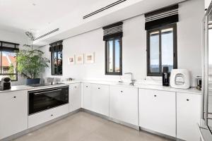una cocina blanca con armarios blancos y ventanas en Modern 2BR Private House Neve Tsedek by HolyGuest en Tel Aviv