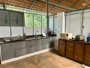 a large kitchen with a sink and a microwave at Gloria Homestay ,Thrissur in Trichūr