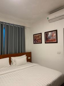 - une chambre avec 2 lits avec des draps blancs et une fenêtre dans l'établissement A25 Hotel - Đội Cấn 2, à Hanoï