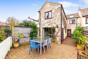 a patio with a table and chairs in front of a house at Wherry Cottage, Sleeps 8 in Southwold