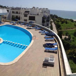 een zwembad met stoelen en parasols op een gebouw bij Apartamento Maria in Lagos