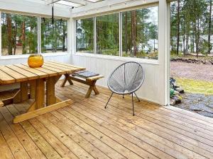 une véranda avec une moustiquaire, une table en bois et une chaise dans l'établissement Holiday home Mönsterås VII, à Mönsterås