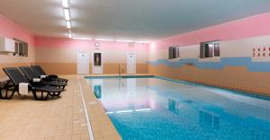 a swimming pool in a room with chairs and a table at Hotel Schwarz in Nové Hamry