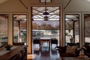 a dining room with glass doors and a table at The Boathouses at Leaves & Fishes in Lovedale