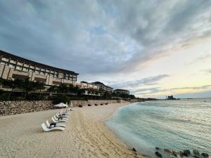a beach with white lounge chairs and the ocean at Dusit Thani Mactan Cebu Resort in Mactan