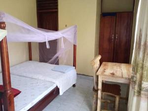 a bedroom with a bed and a desk and a bed and a table at Kibale Eco-Home in Bigodi