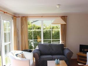 a living room with a couch and a large window at Chalet with garden near Wadden Sea in Tzummarum