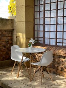 einen Tisch und zwei Stühle auf einer Terrasse in der Unterkunft Thorntree Self Catering Apartment, Witbank in Witbank