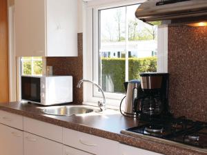 a kitchen counter with a sink and a microwave at Chalet with garden near Wadden Sea in Tzummarum