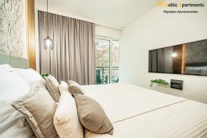 a bedroom with a large white bed with pillows at Baltic Apartments - Matejki 17 in Świnoujście