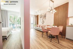 a living room and dining room with a table and pink chairs at Baltic Apartments - Matejki 17 in Świnoujście