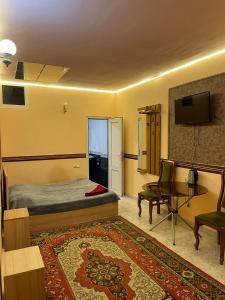 a bedroom with a bed and a table and a tv at CITRUS Guest House in Yerevan