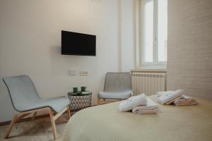 1 dormitorio con 1 cama, 2 sillas y TV en Una casa a San Giacomo x2, en Trieste