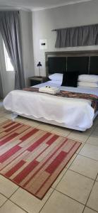 a large bed in a bedroom with a rug at Grey lourie Guesthouse in Zeerust