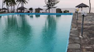 - une piscine bleue à côté de l'océan dans l'établissement Zuri Luxe 3BR Penthouse- Silversands Beach Malindi, à Malindi