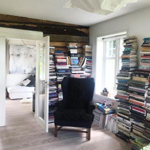 ein Zimmer mit einem großen Stapel Bücher und einem Stuhl in der Unterkunft Magnor House in Eidskog, Hedmark close to The Plus and Magnor Glassverk in Magnor