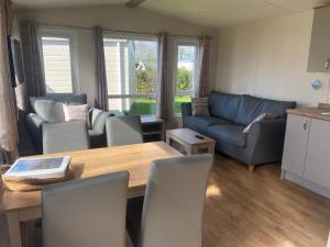 een woonkamer met een tafel en een blauwe bank bij Camping de Duinhoeve Chalet Vogel not for companies in Nieuw-Haamstede