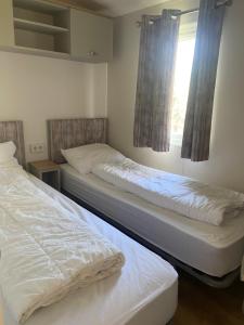 twee bedden in een kamer met een raam bij Camping de Duinhoeve Chalet Vogel not for companies in Nieuw-Haamstede