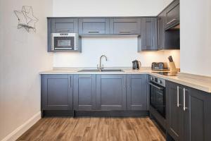 a kitchen with dark blue cabinets and a sink at Host & Stay - Seaview Retreat in Whitby