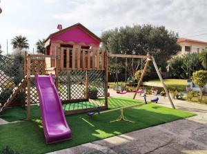 een speeltuin met een paarse glijbaan en een schommel bij Villa Calipso - Appartamento in Villa con giardino e wi-fi in Ovile la Marinella