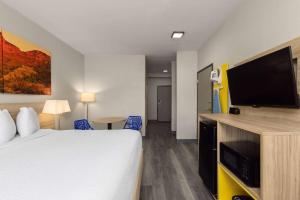 a hotel room with a bed and a flat screen tv at Days Inn & Suites by Wyndham Tucson/Marana in Tucson