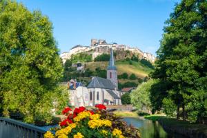 un castillo en una colina con un río y flores en Gîte de ville appartement Location de vacance - St-Flour - 6-8 Personnes dans le Cantal, en Saint-Flour