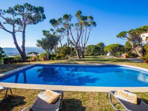 una piscina con 2 sillas de césped y árboles en Villa Boreal, en Calonge