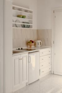 a white kitchen with white cabinets and a stove at Nevma Suites in Firostefani