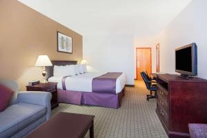 a hotel room with a bed and a tv at Ramada by Wyndham Red Deer Hotel & Suites in Red Deer