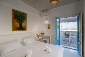 a white bedroom with a bed and a view of the ocean at Nevma Suites in Firostefani