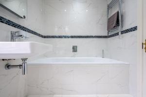 a white bathroom with a tub and a sink at Spacious, Bright & Cosy ~ Ideal Victoria Location! in London