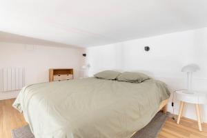 a white bedroom with a large bed and a table at Lille Bel appartement Cosy avec Mezzanine in Lille